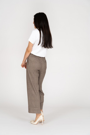 Vista posteriore di tre quarti di una giovane donna confusa in calzoni e maglietta che si tengono per mano
