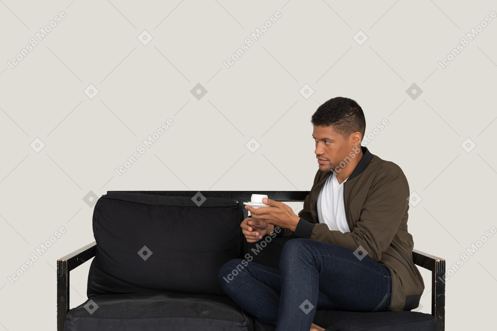 Вид в три четверти молодого человека, мечтающего, сидящего на диване с чашкой кофе