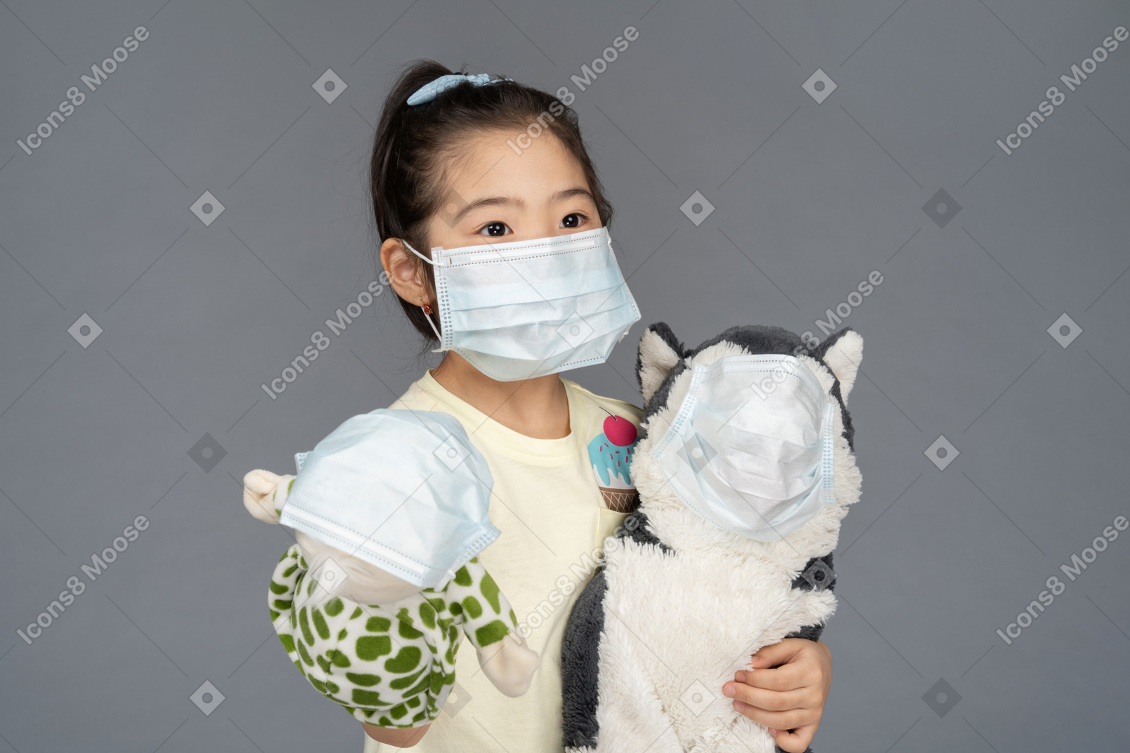 Close-up de uma menina segurando dois brinquedos, todos usando máscaras