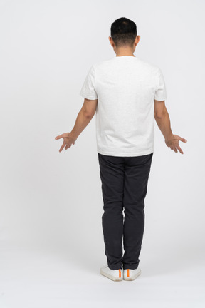 Vista posteriore di un uomo in abiti casual in piedi con le braccia tese