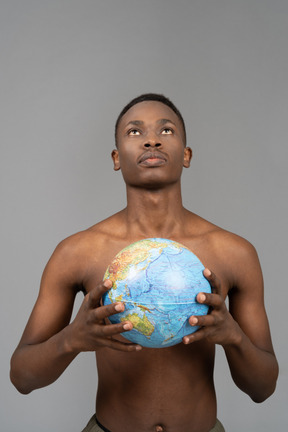 A shirtless young man holding the earth globe