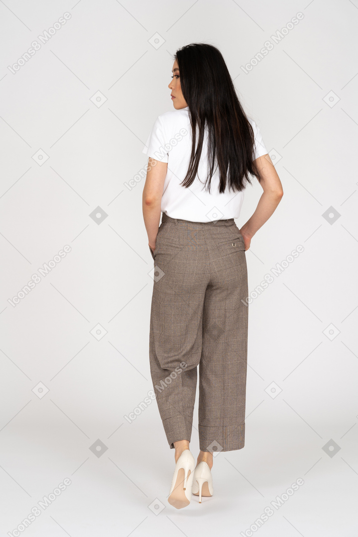 Vista posteriore di una giovane donna che cammina in calzoni e t-shirt