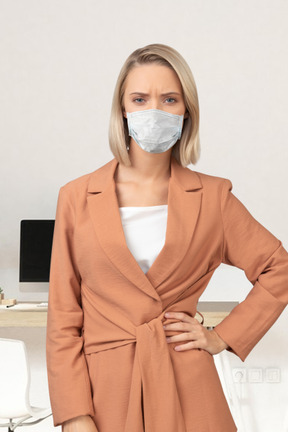 A woman wearing a face mask standing in front of a desk