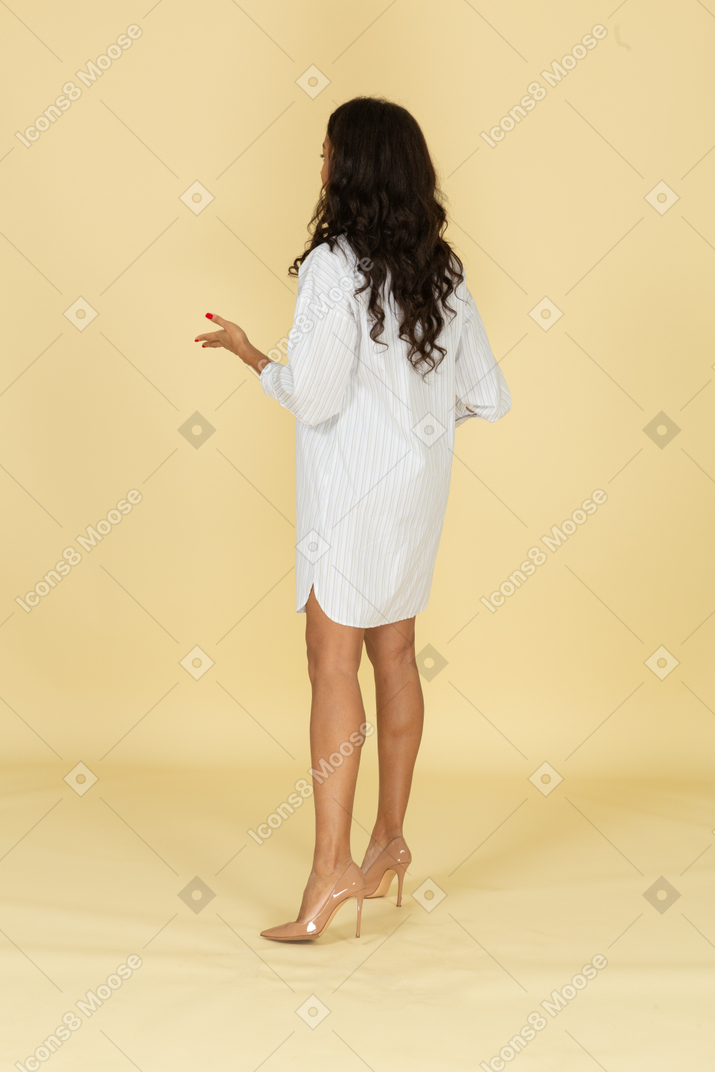 Три четверти сзади на вопрошающую темнокожую молодую женщину в белом платье