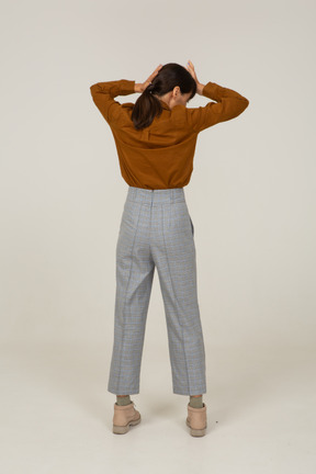 Back view of a young asian female in breeches and blouse touching head