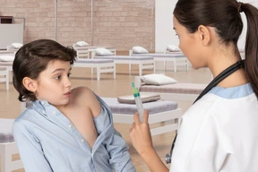 Nurse showing syringe to frightened boy