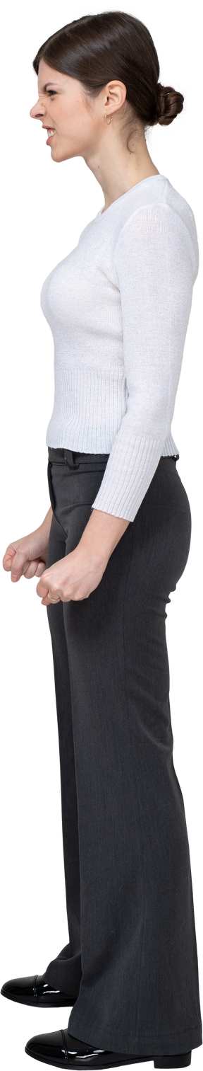 Vista lateral de uma mulher furiosa com roupas de escritório cerrando os punhos