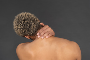 Back view of a shirtless afro man touching his neck