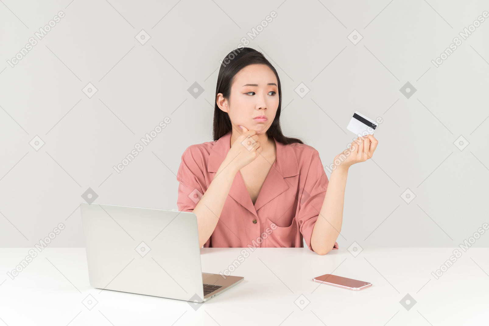 Sad looking young asian woman doing online shopping