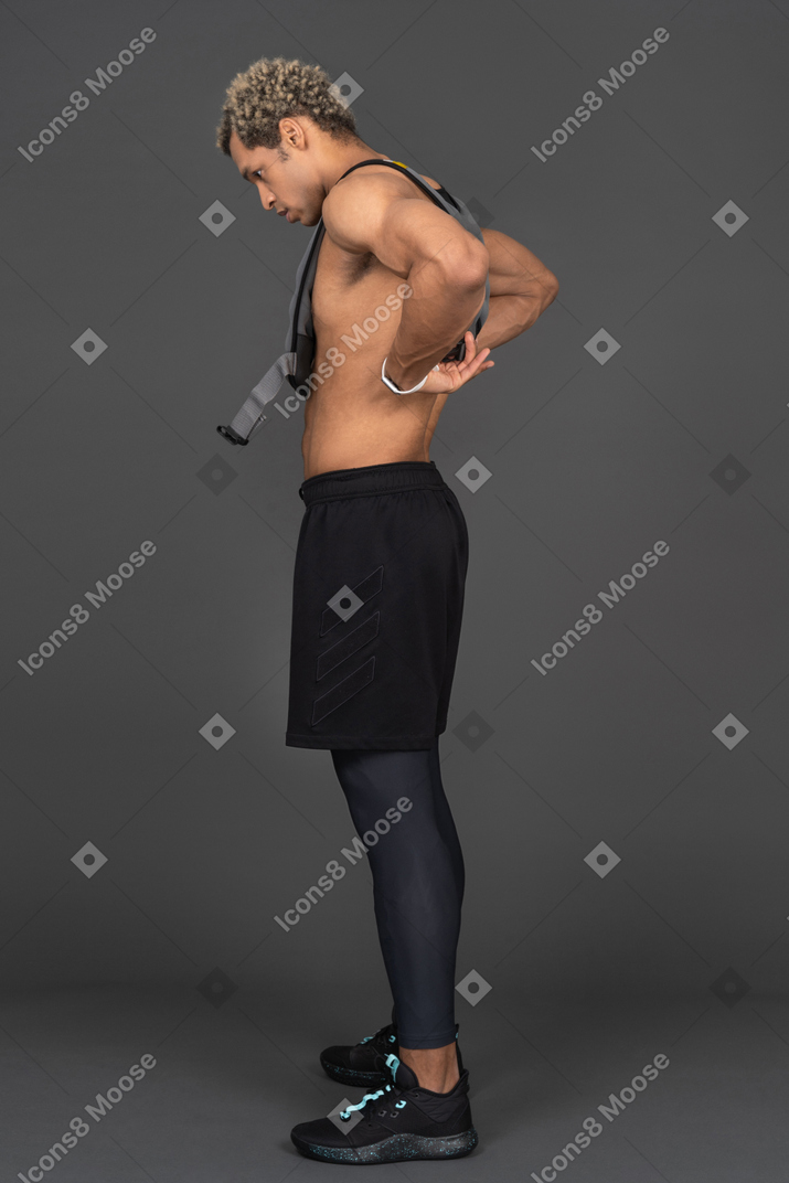 Vista laterale di un uomo afro a torso nudo che si aggiusta il giubbotto