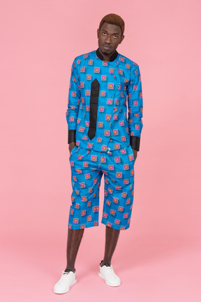 Black man in blue pajamas standing on pink background