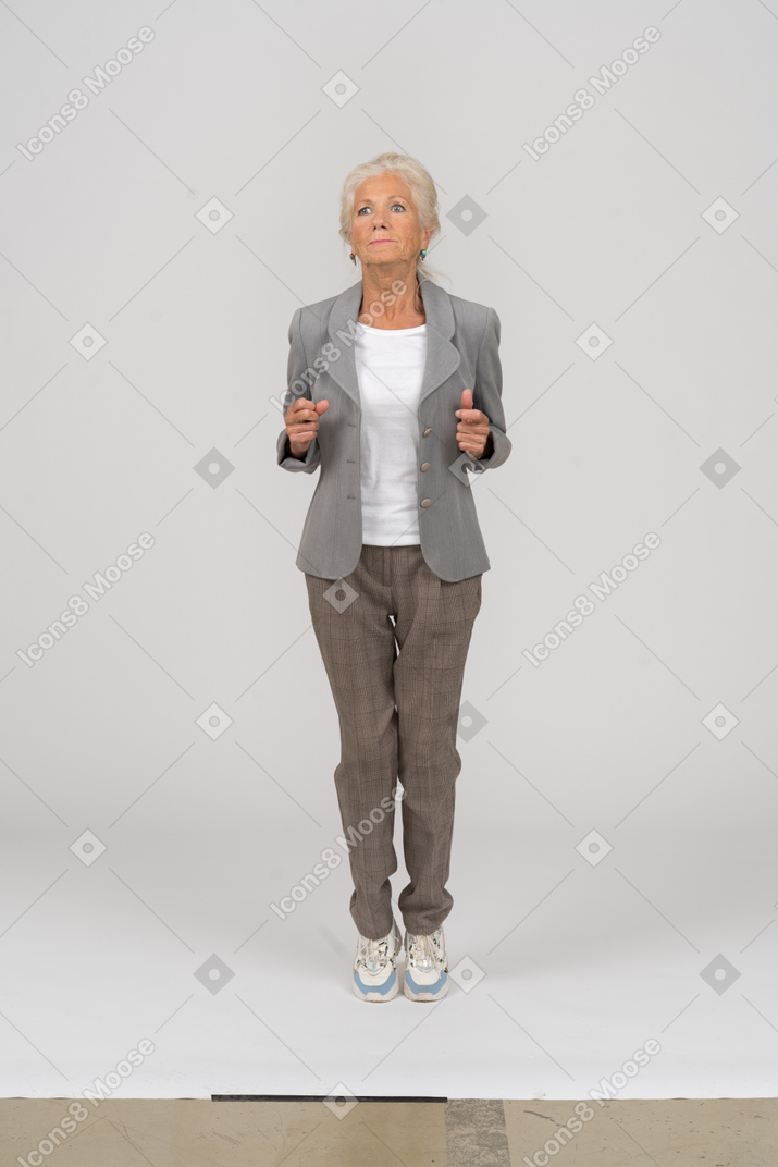 Front view of an old lady in suit standing on toes