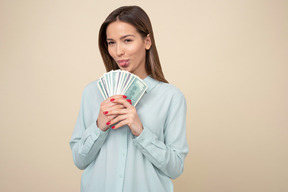 Attractive woman holding dollar bills and showing her tongue
