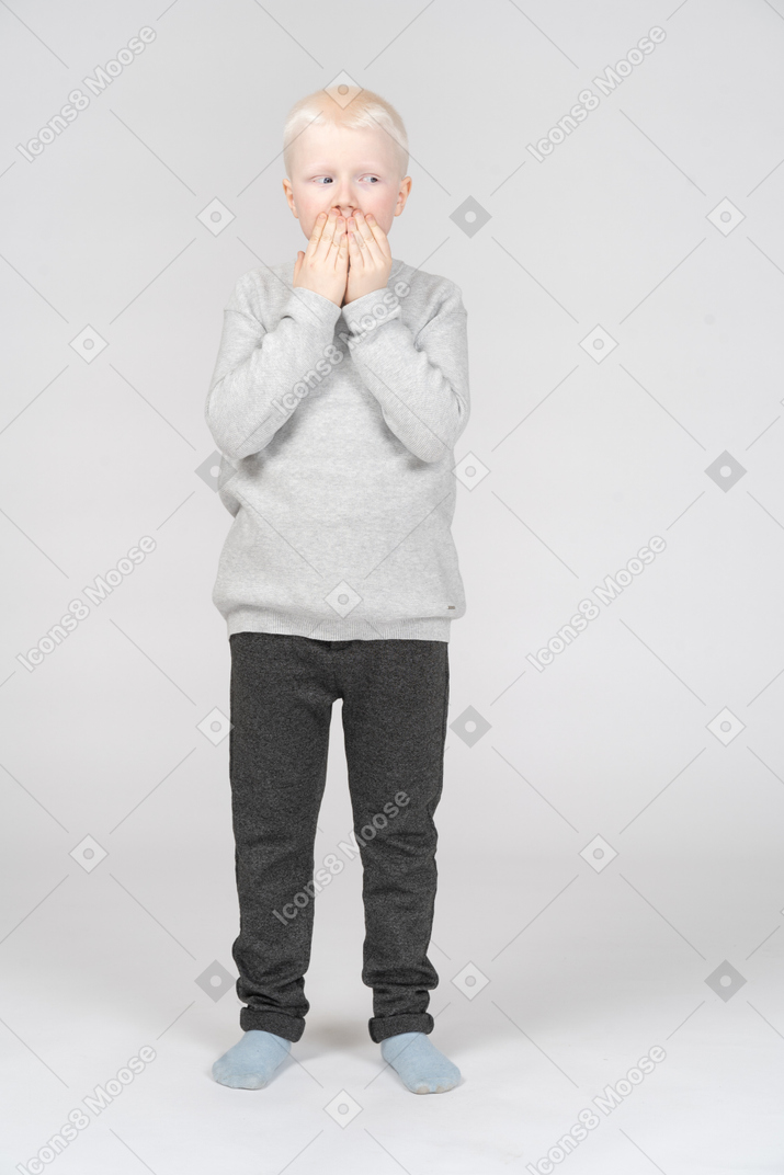 Niño pequeño que cubre su boca con las manos