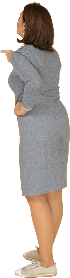 Vista laterale di una donna in abito grigio che indica con un dito