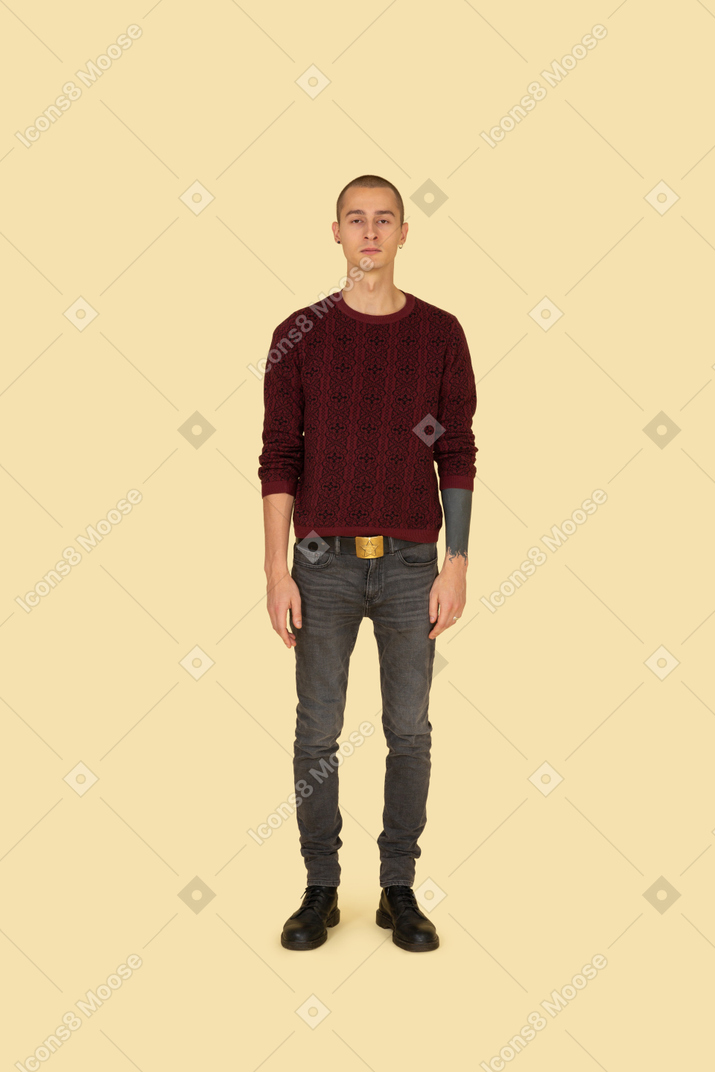 Молодой человек в красном свитере, стоя на месте, вид спереди