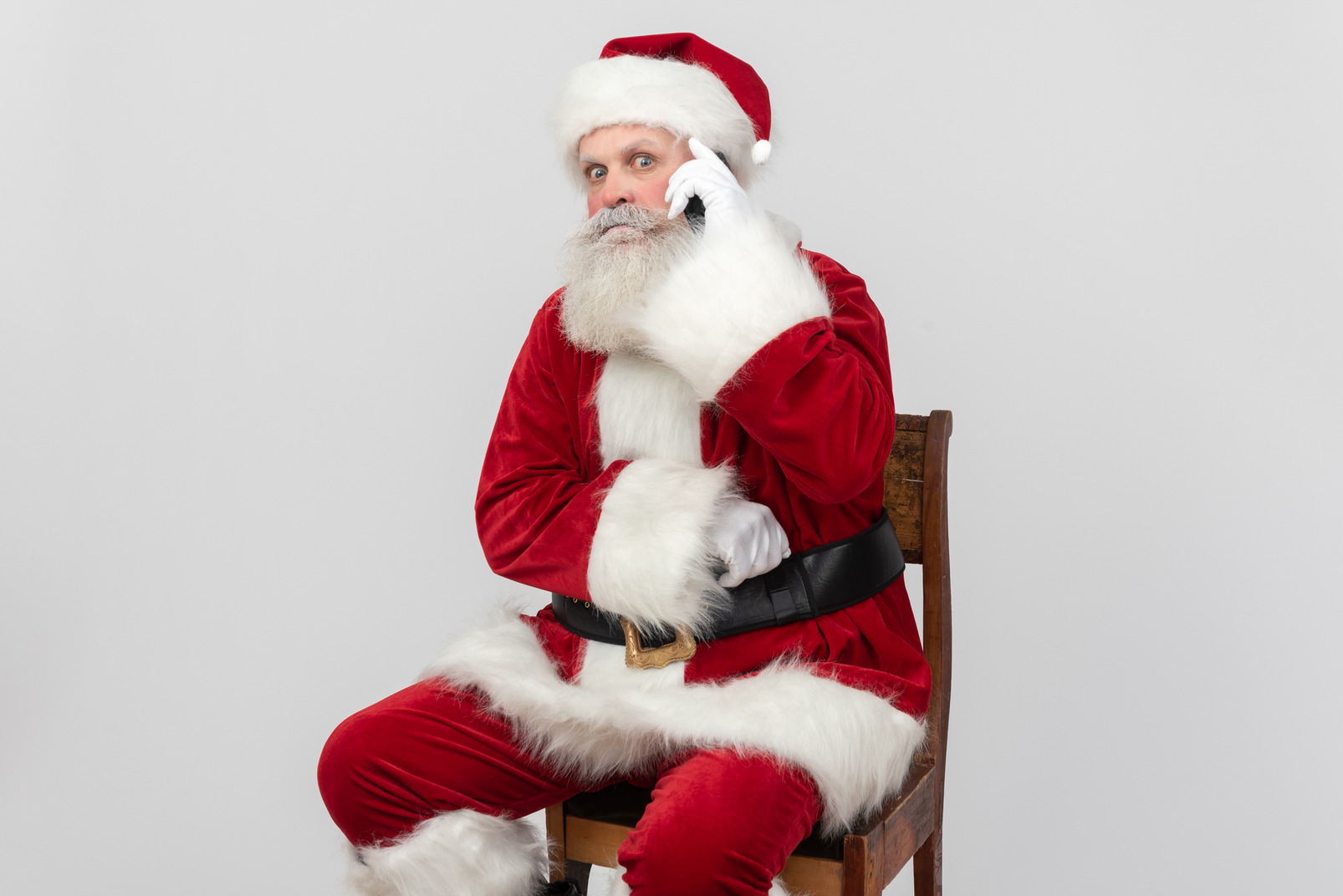 Pensive santa claus sittting and talking on the phone