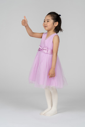 Портрет милой маленькой девочки, показывающей большие пальцы руки вверх
