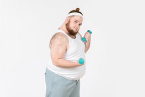 Serious looking big guy in sportswear lifting hand weights