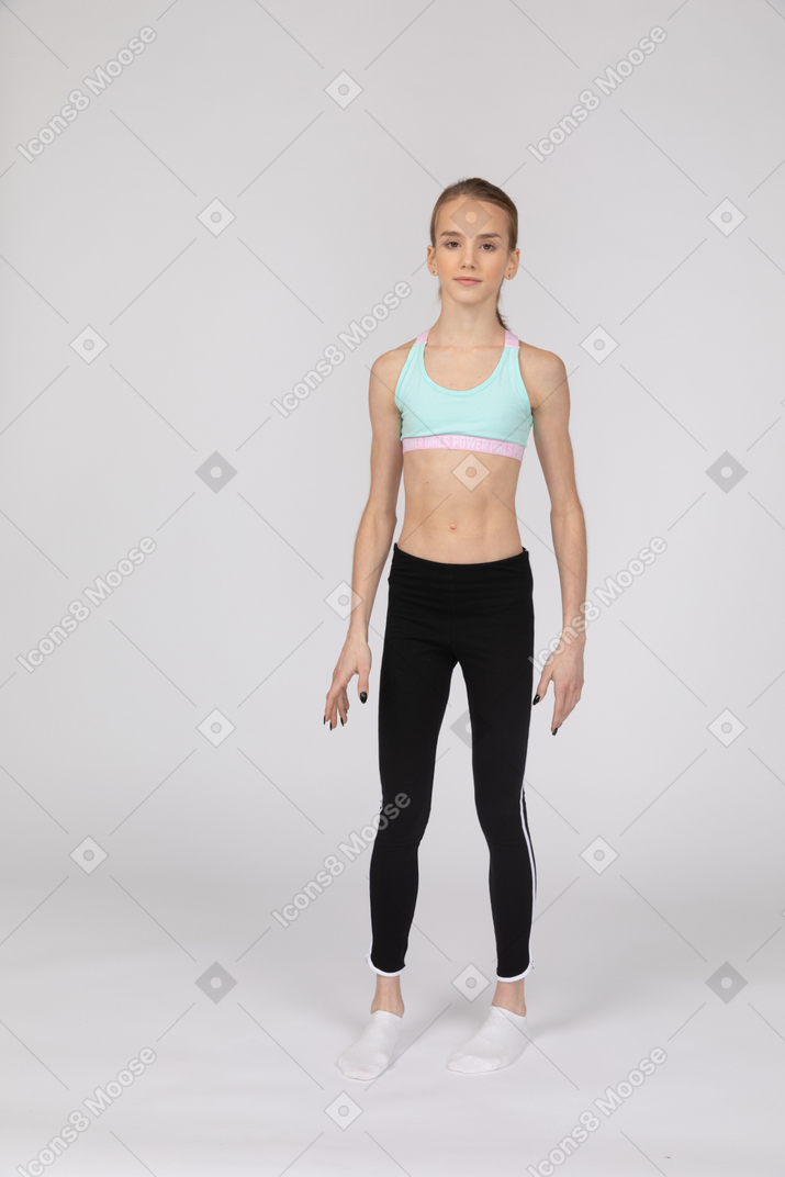 Vista frontal de uma adolescente em roupas esportivas olhando para a câmera