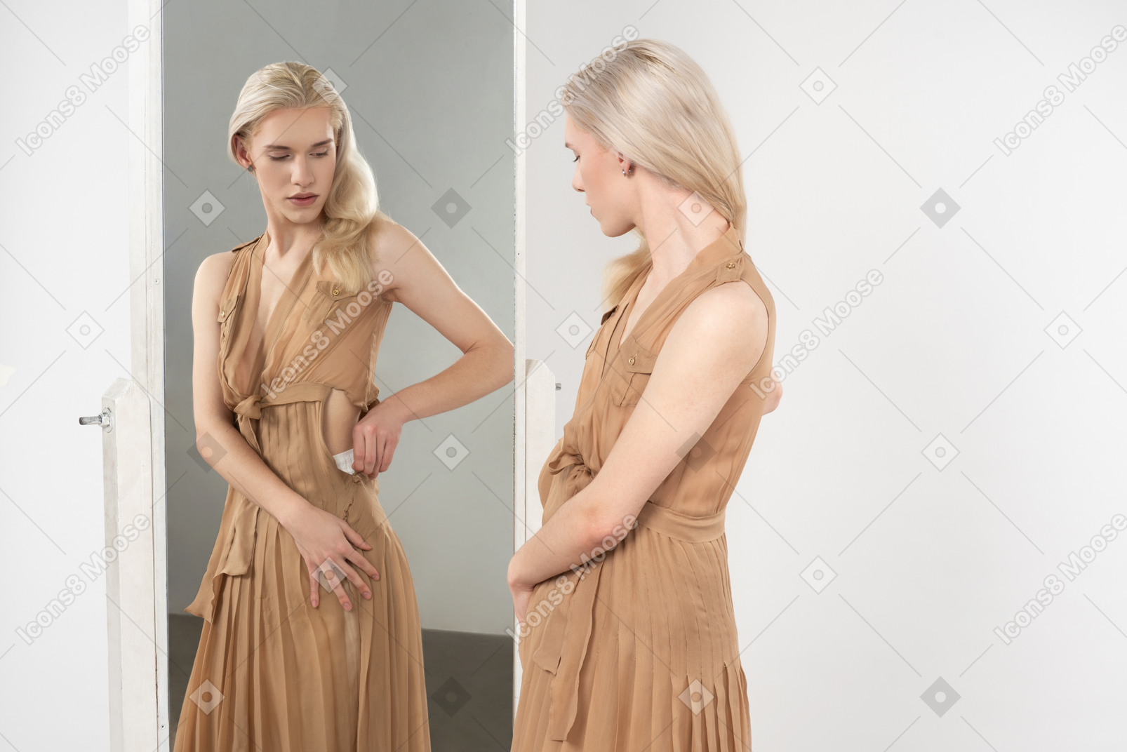 거울 앞에서 옷의 다른 항목을 입고 엉덩이에 흰 수건에 젊은 blond-haired 사람