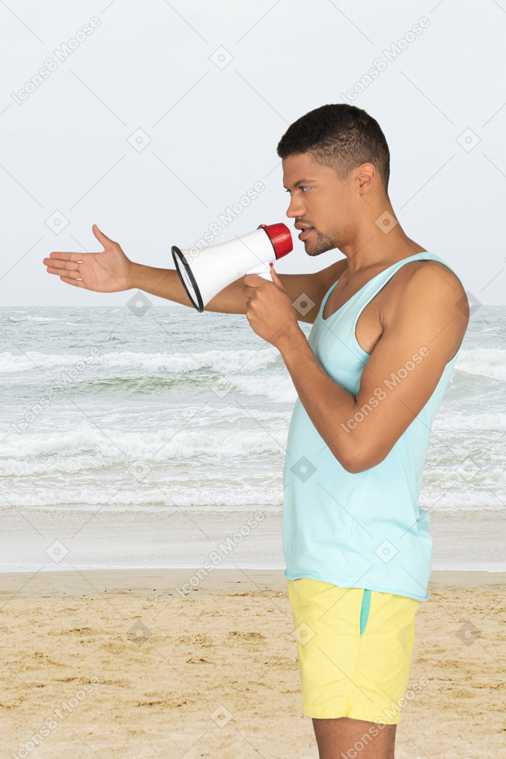 A man standing on a beach holding a megaphone