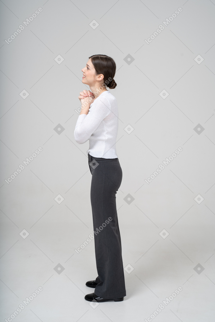 Side view of a woman in black pants and white blouse making praying gesture