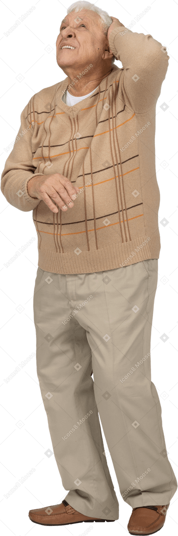 Vue de face d'un vieil homme en vêtements décontractés debout avec la main derrière la tête et levant les yeux