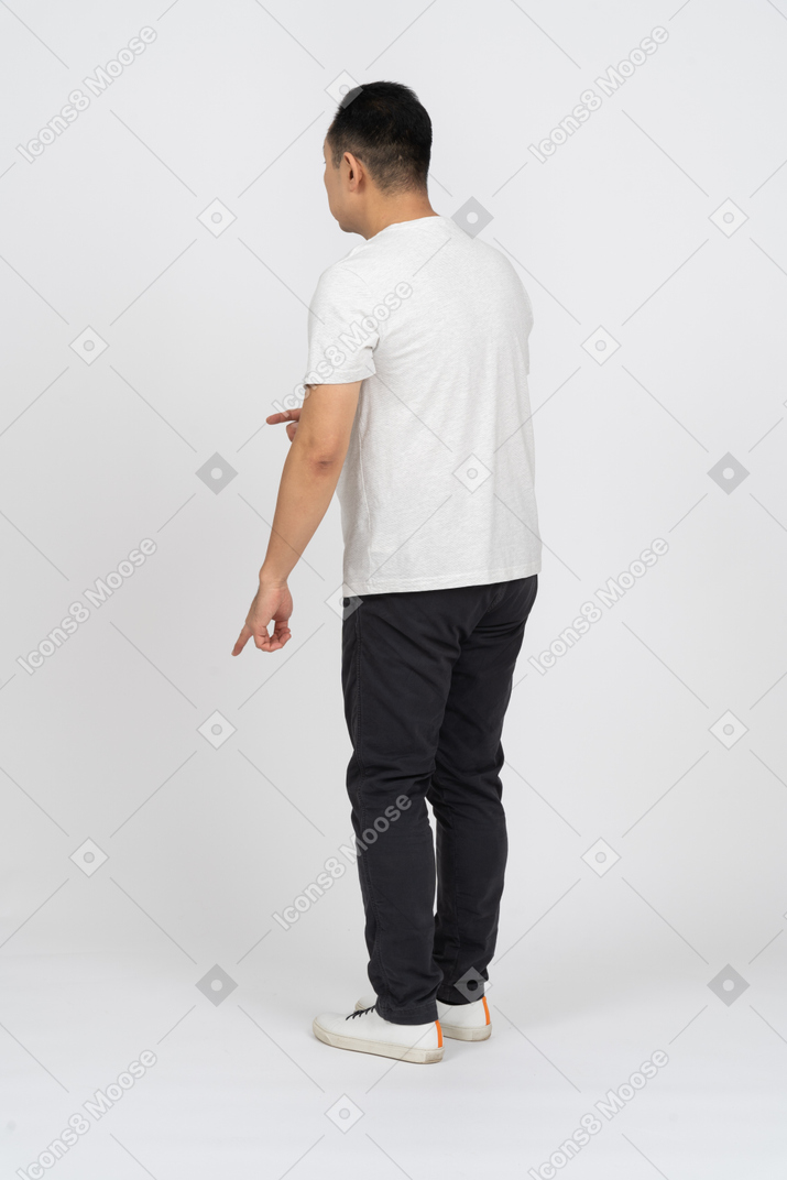 Vista de tres cuartos de un hombre con ropa informal apuntando hacia abajo con el dedo