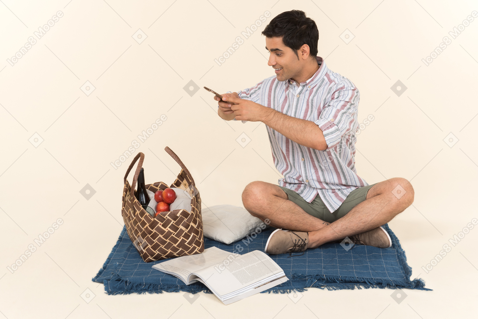 Giovane ragazzo caucasico seduto sulla coperta e fare una foto del cestino da picnic