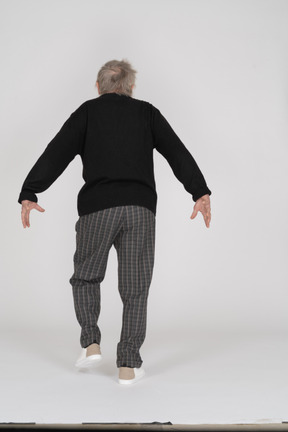 Anciano caminando con los brazos extendidos hacia atrás