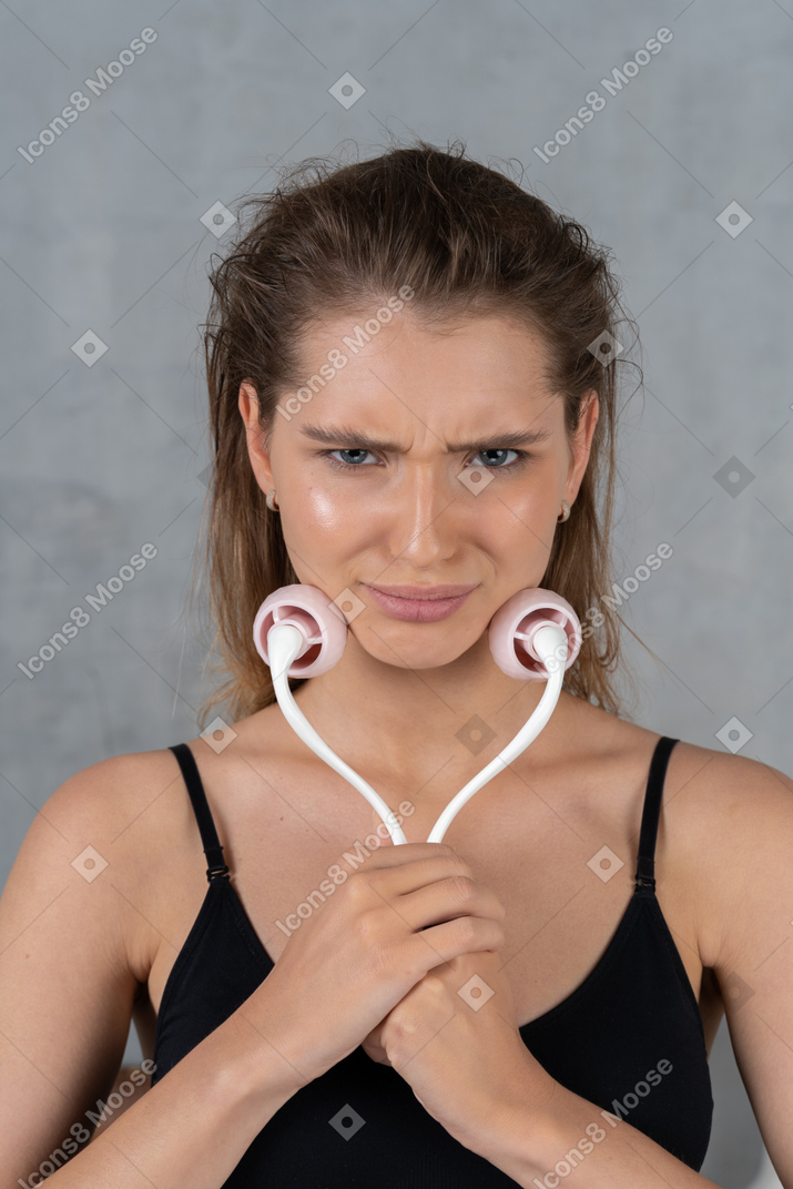Primo piano di una giovane donna che usa il rullo facciale mentre sembra scontento