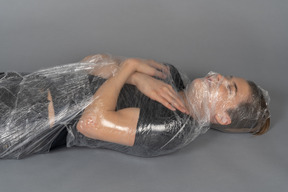 Junger mann mit geschlossenen augen in plastik verpackt