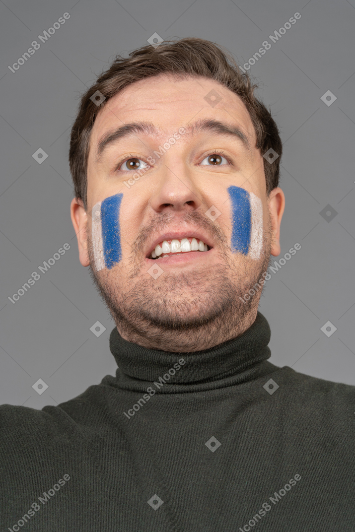 파란색 및 흰색 얼굴 예술로 남성 축구 팬의 초상화