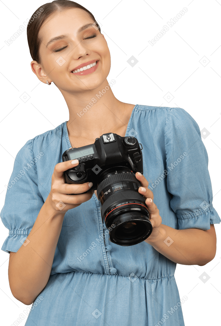 Front view of a smiling young woman in blue checking pictures