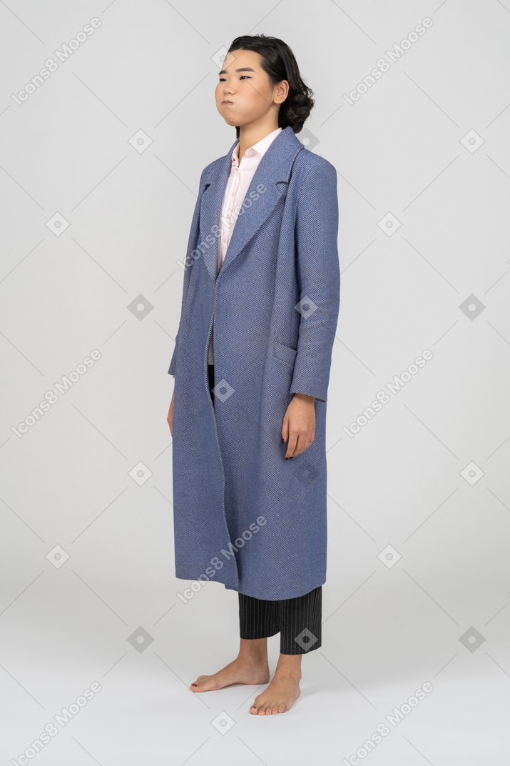 Woman in blue coat with her cheeks puffed out