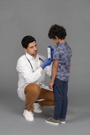 Médico mostra seringa para um menino