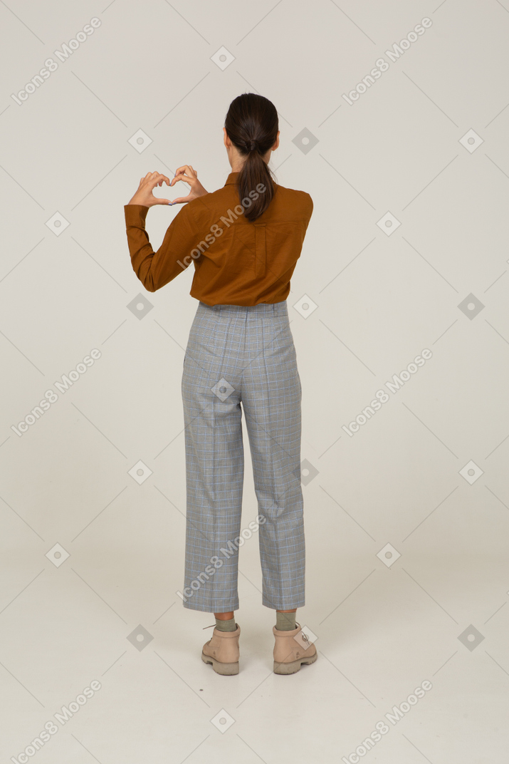 Back view of a young asian female in breeches and blouse showing heart gesture