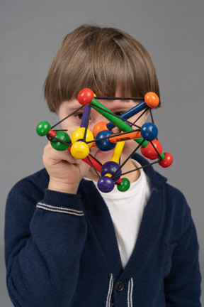 Garotinho, olhando para a câmera através de brinquedo colorido