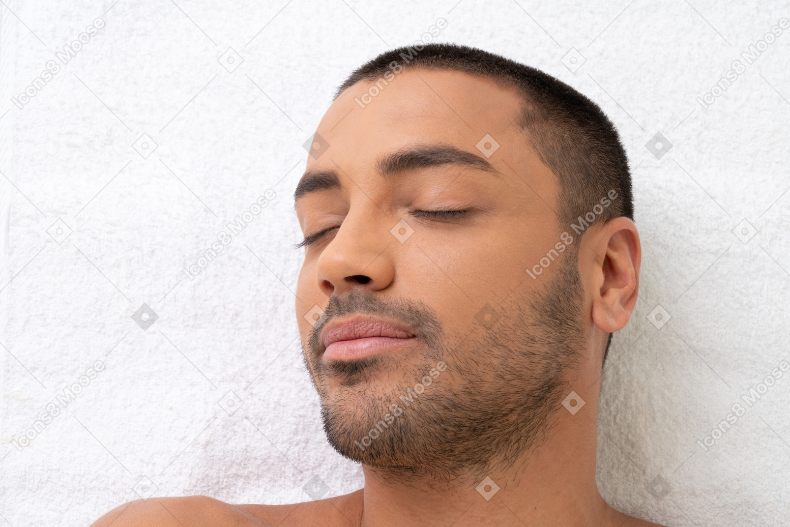 Красивый молодой человек лежал на белом полотенце с закрытыми глазами