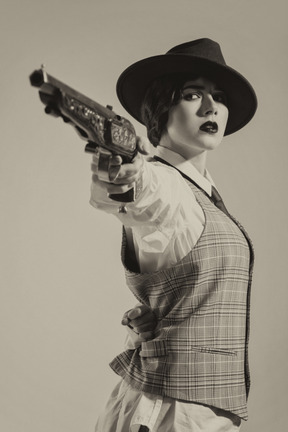 Donna sicura di sé in cappello che mira la pistola con una mano
