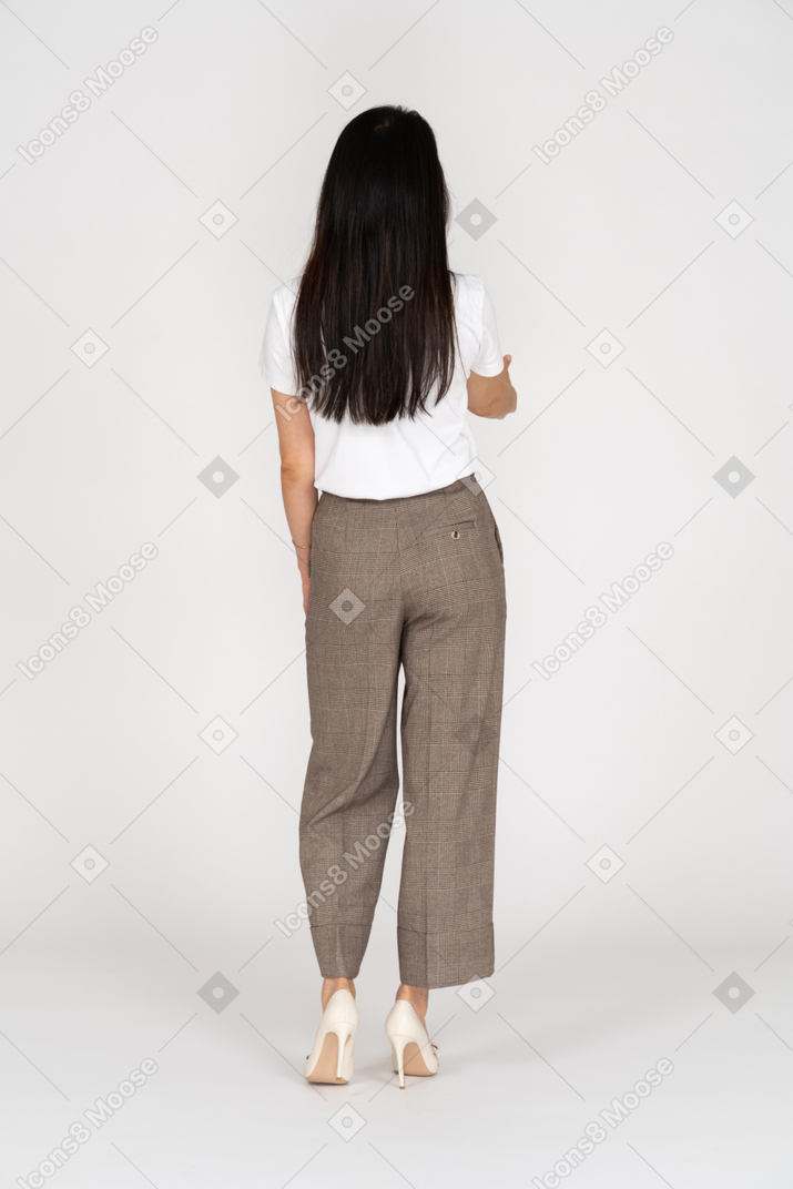 Back view of a greeting young lady in breeches and t-shirt outstretching her hand