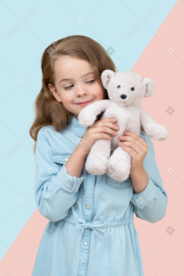 A little girl holding a white teddy bear