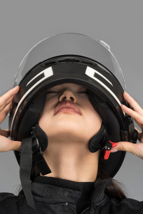 A young woman taking off a helmet