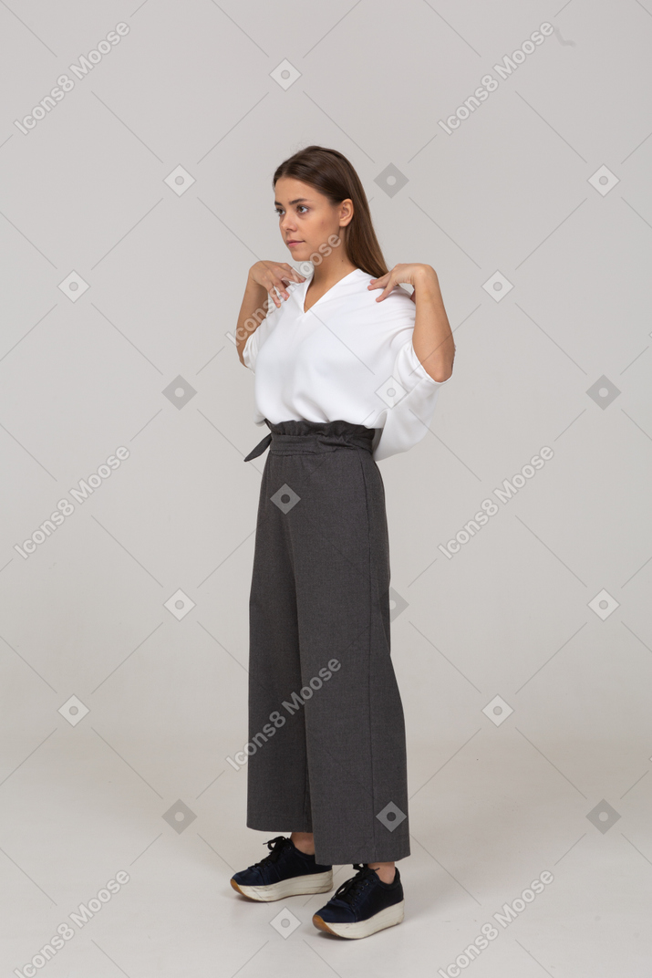 Three-quarter view of a young lady in office clothing touching her shoulders
