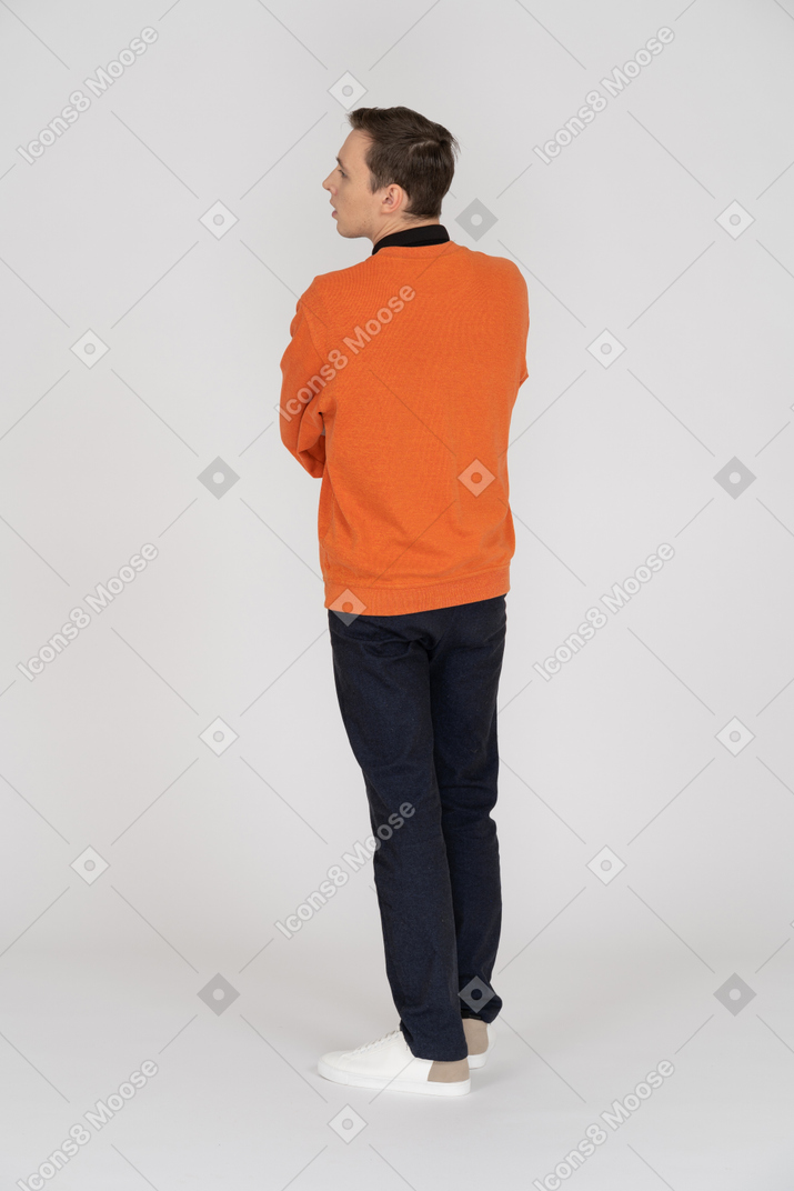 A man in an orange sweater is facing away from the camera