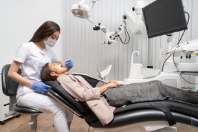 Longitud total de una dentista examinando a su paciente acostada en un gabinete de hospital