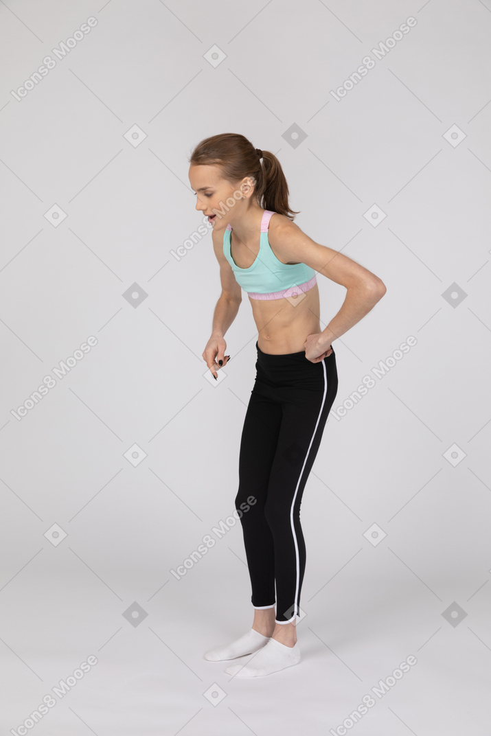 Vista lateral de una jovencita en ropa deportiva levantando la mano y argumentando