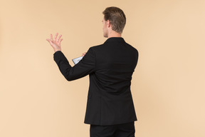 A white man in a fully black suit holding the quran