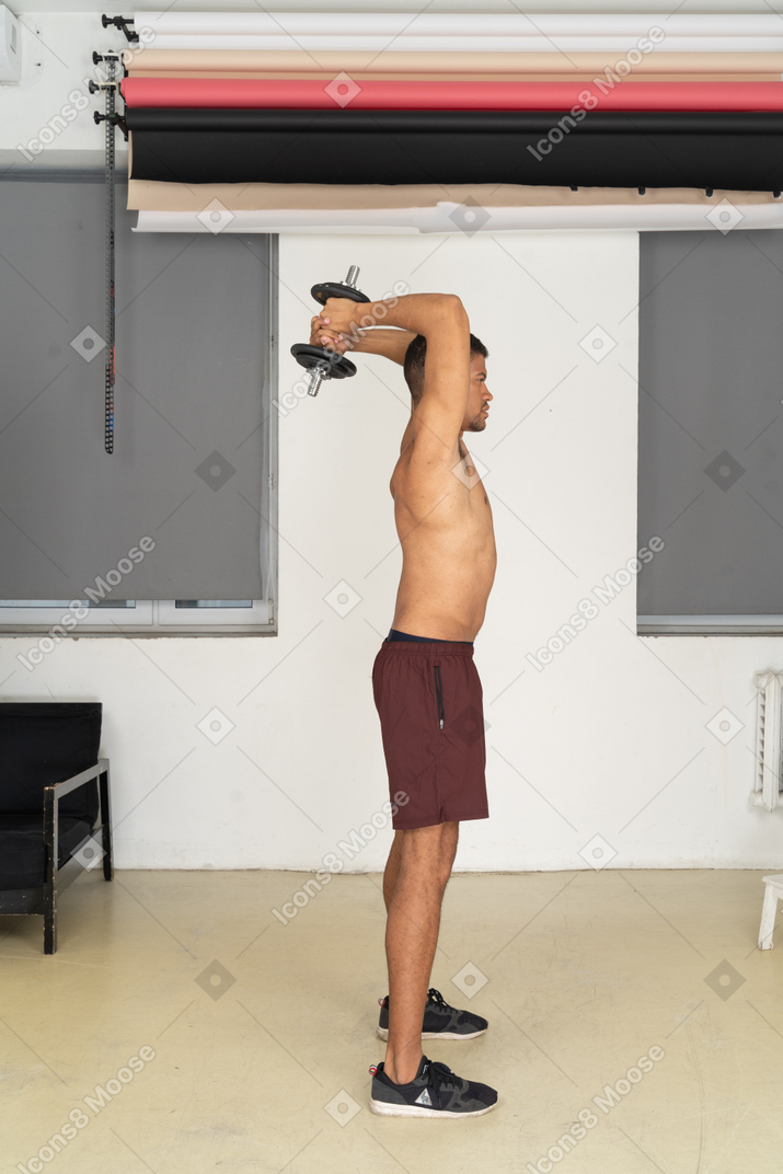 Vista lateral do homem se exercitando com halteres